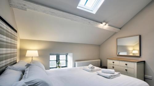 a bedroom with a large white bed and a mirror at The Snug - Llyn Peninsula in Pistyll