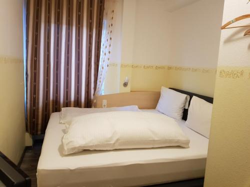 a bed with white sheets and pillows in a room at Hotel Dietrich in Neu Isenburg