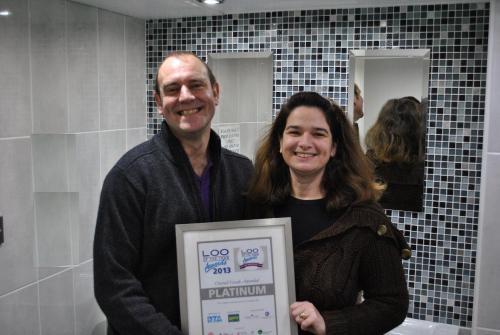 a man and a woman holding a sign in a bathroom at The Longboat Inn in Penzance