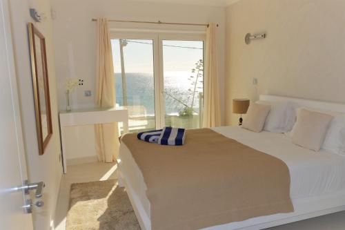 a white bedroom with a bed and a large window at Casa do Mar in Luz