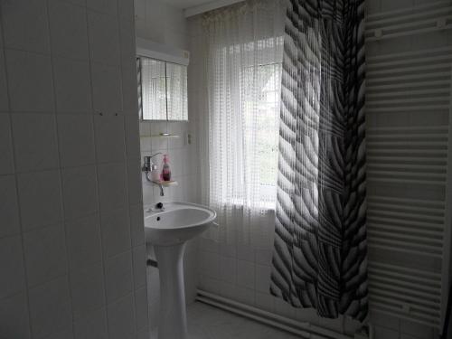 a white bathroom with a sink and a window at Penzion SPICAK in Železná Ruda