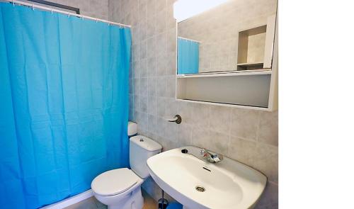 baño con aseo blanco y cortina de ducha azul en Rentalmar Casa Horus en Miami Platja