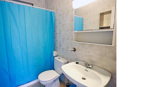 a bathroom with a white toilet and a blue shower curtain at Rentalmar Casa Horus in Miami Platja