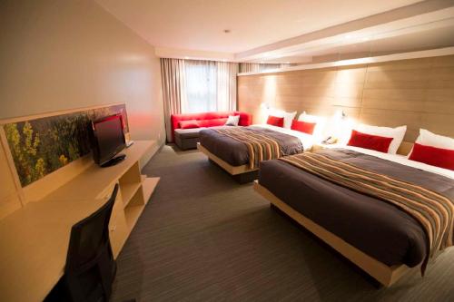 a hotel room with two beds and a flat screen tv at Gîte du Mont-Albert - Sepaq in Sainte-Anne-des-Monts