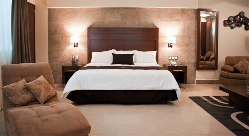 a bedroom with a large bed and two chairs at Hotel Ecce Inn & Spa in Silao