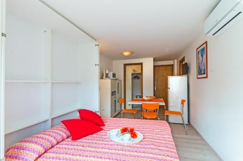 ビビオーネにあるLaguna Grande monolocaliのベッドルーム1室(赤い枕と皿付きのベッド1台付)