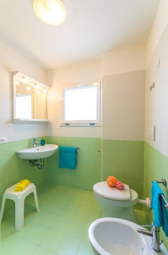 a green bathroom with a toilet and a sink at Laguna Grande monolocali in Bibione