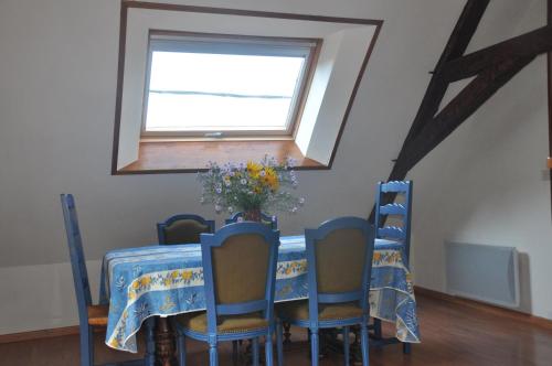 une table à manger avec des chaises bleues et une fenêtre dans l'établissement Gîte la Chamoussière, à Saint-Mury-Monteymond