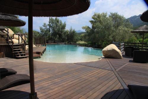 a swimming pool with a wooden deck and an umbrella at Lecci e Murta in Propriano