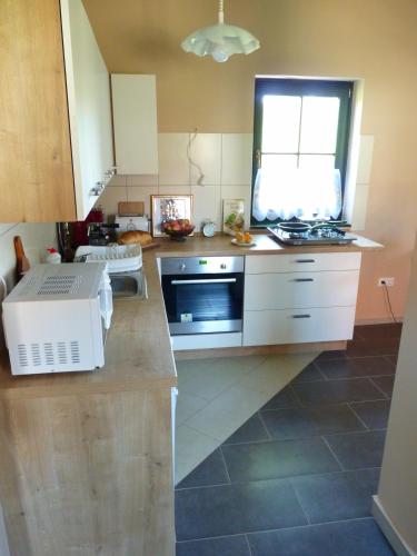 a kitchen with white cabinets and a window at Két Kapu Udvarház in Szentlászló