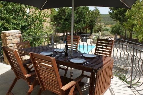 a wooden table with chairs and an umbrella on a patio at Pradines in Saint-André-de-Roquelongue