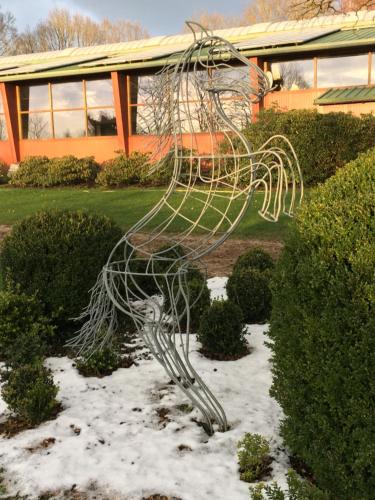 a metal sculpture in the snow in front of a building at Huck’s Ferienhäuser in Borstel