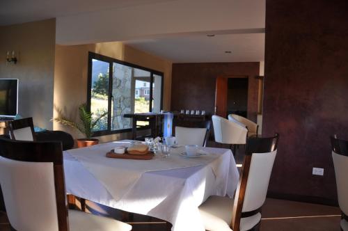 a dining room with a white table and chairs at Hostería La Chira in San Martín de los Andes