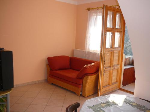 a living room with a red couch and a window at Porkoláb Apartmanház in Gyenesdiás