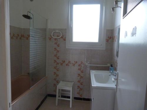 La salle de bains est pourvue d'un lavabo, d'une douche et d'un tabouret. dans l'établissement Gite La Rizière, à Vic-en-Bigorre