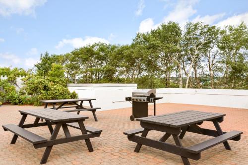three picnic tables and a grill on a brick patio at Travelodge by Wyndham Sydney in Sydney