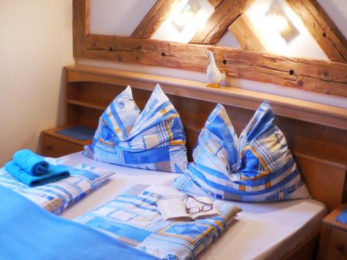 Una cama con almohadas azules y blancas y un pájaro en Landhaus Wiederkehr, en Ramsau am Dachstein