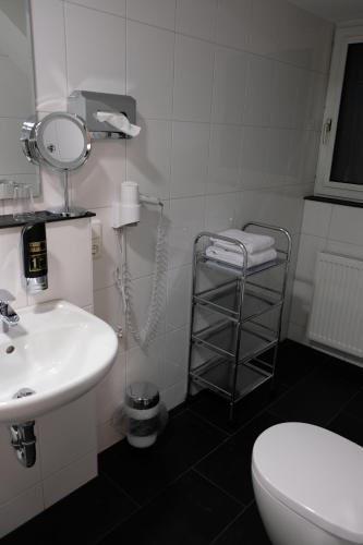 
a bathroom with a toilet, sink, and mirror at Minx – CityHotels in Aachen
