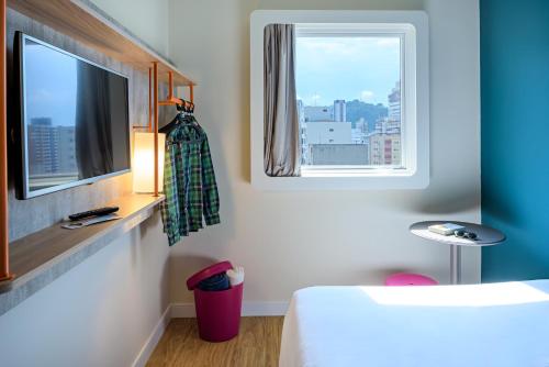 a room with a bed and a tv and a window at ibis budget Santos Gonzaga in Santos