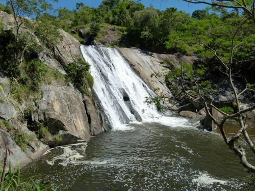 a waterfall on the side of a mountain with water at Atalho Guest House in Cunha