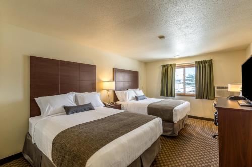 um quarto de hotel com duas camas e uma secretária em Cobblestone Inn & Suites - Merrill em Merrill