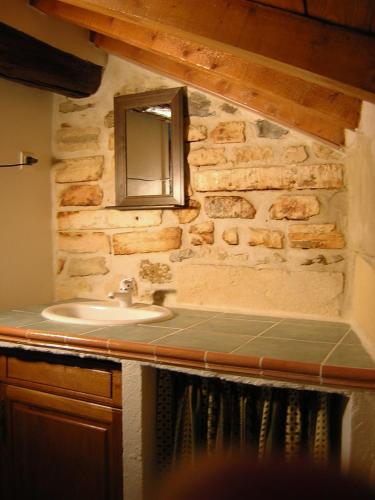 La salle de bains est pourvue d'un lavabo et d'un miroir sur un mur en pierre. dans l'établissement Luclem, à Arles