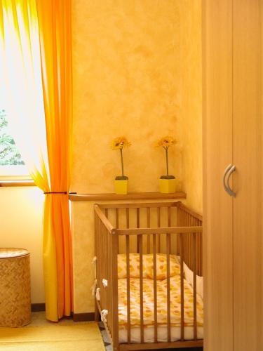 a baby crib in a room with an orange curtain at Casa Cinzia in Gravedona