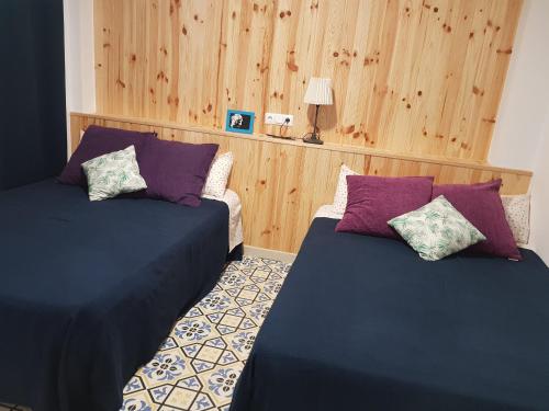 two beds in a room with wood paneling at Apartamento junto a la playa by Hugo Beach in Gandía