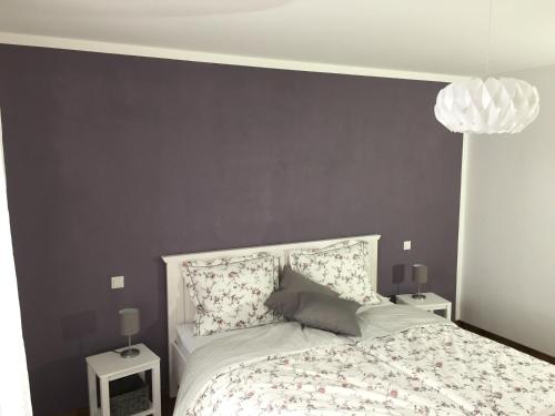 ein Schlafzimmer mit einem Bett mit einer grauen Wand in der Unterkunft Rudis in Monschau