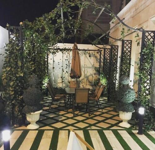 a patio with a table and chairs and an umbrella at شالية النخلة in Unayzah