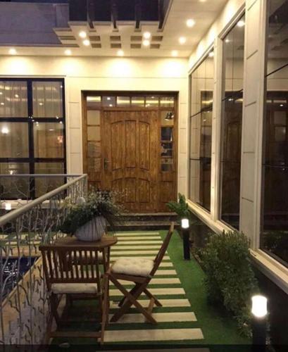 a porch with two chairs and a table and a wooden door at شالية النخلة in Unayzah
