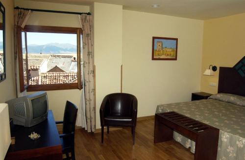 a bedroom with a bed and a television and a window at Hotel Spa La Casa Mudéjar in Segovia