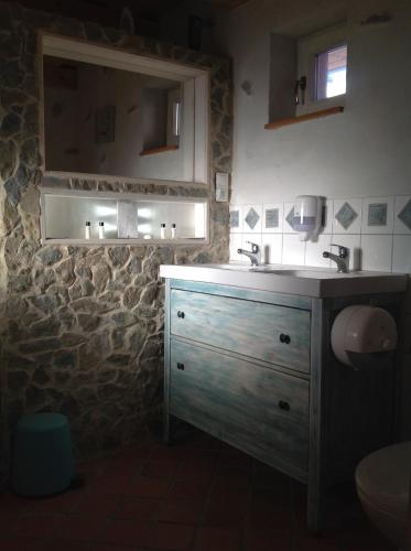 a bathroom with a sink and a stone wall at Kopanický dvor in Hodruša