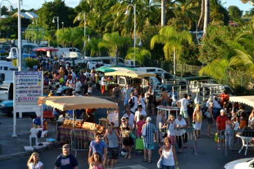 a crowd of people walking around a market with umbrellas at Cactus Anse Des Rochers in Saint-François