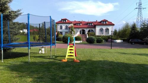 einen Spielplatz in einem Hof mit einem Haus im Hintergrund in der Unterkunft Pod Lwami in Błonie