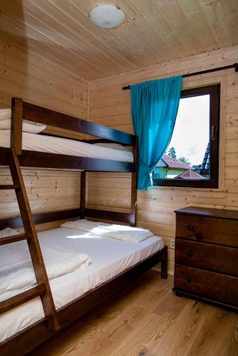 a bedroom with two bunk beds and a window at Wisełka Domki Letniskowe NEMO in Wisełka
