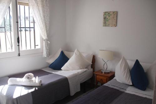 a bedroom with two beds with blue and white pillows at Vista Bahia II Apartments- top floor with balcony views & ground floor with garden and BBQ in Albir