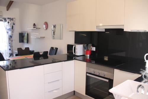 a kitchen with white cabinets and black counter tops at Vista Bahia II Apartments- top floor with balcony views & ground floor with garden and BBQ in Albir