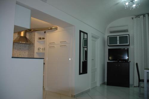 a kitchen with white cabinets and a tv in a room at Casa Duomo in Amalfi