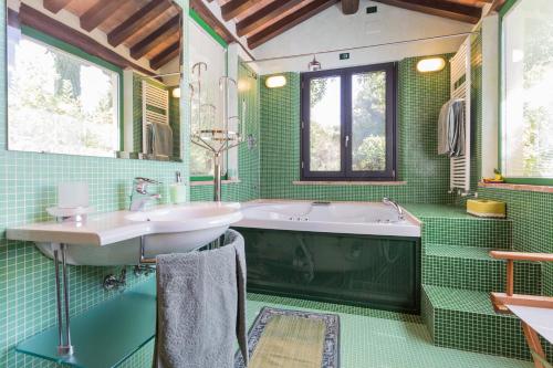a green bathroom with a tub and a sink at La Vittoria 10 – La Soglia della Val d’Orcia in Chianciano Terme