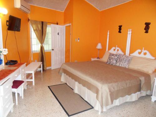 um quarto com uma cama grande e paredes cor-de-laranja em Whistling Villa Runaway Bay em Runaway Bay