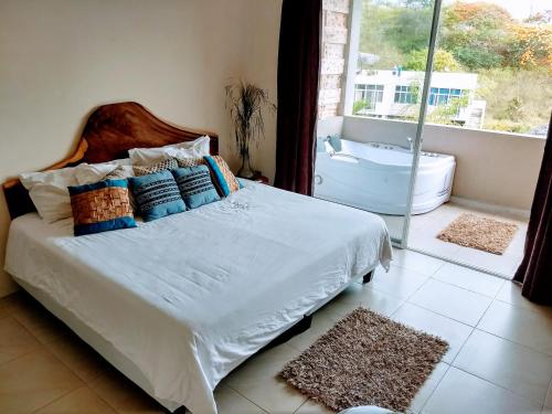a bedroom with a bed and a bathroom with a tub at ME Hotel & Villas - Montañita Estates in Montañita