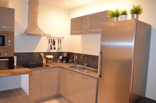 une cuisine avec un réfrigérateur en acier inoxydable et un évier dans l'établissement Gîte de la Merluchette, à Nazelles-Négron