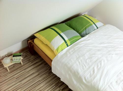 a bedroom with a white bed with green and yellow pillows at Ferienwohnung Schau ins Dorf in Ostercappeln