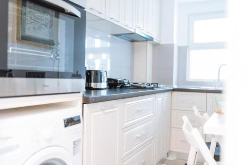 a kitchen with white cabinets and a stove at Luxury City Centre Apartment in Bucharest