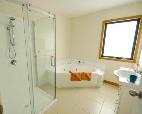 a bathroom with a shower and a tub and a sink at Hill Top Retreat in Nubeena