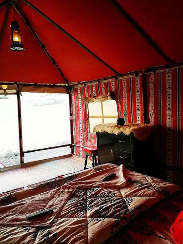 a bedroom with a red tent with a bed and books at Legend Desert camp in Fulayj al Mashāʼikh