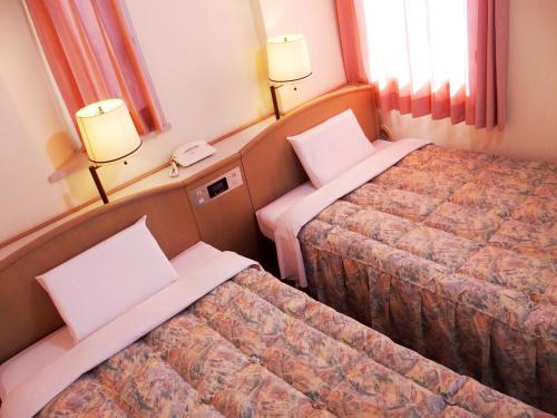 a hotel room with two beds and a phone at Hotel Park Avenue in Tokyo