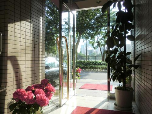 an open glass door with pink flowers in the doorway at Hotel Park Avenue in Tokyo