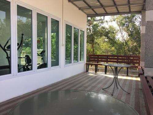 a screened porch with a table and a bench at BanKhun in Nakhon Ratchasima